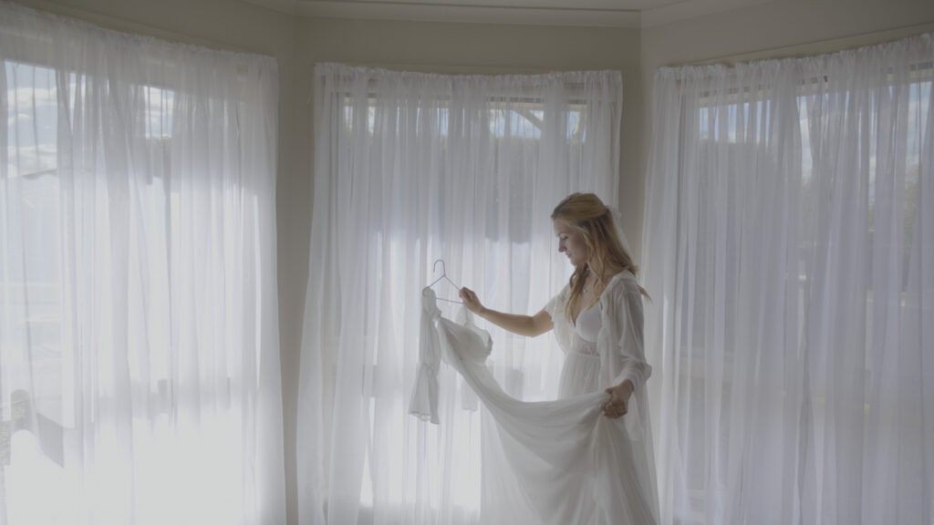 a bride looks at her wedding dress in her wedding film