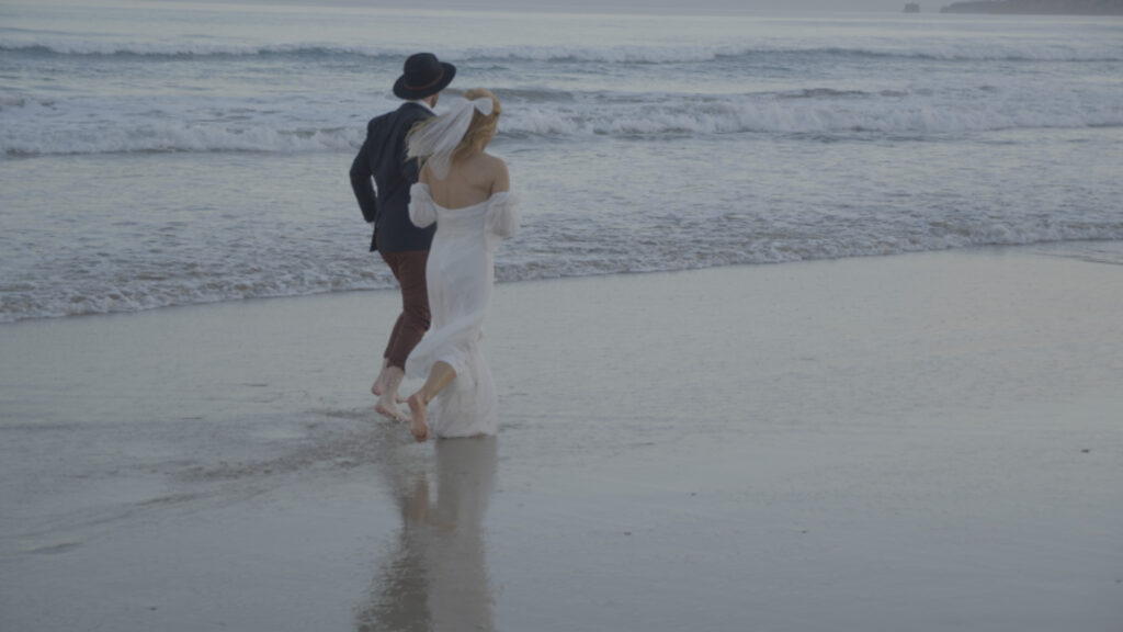 a couple go for a run along a Mornington peninsula beach after their wedding