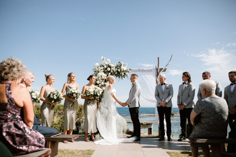 an all smiles sorrento wedding day, with the couple standing under the ocean backdrop arbour