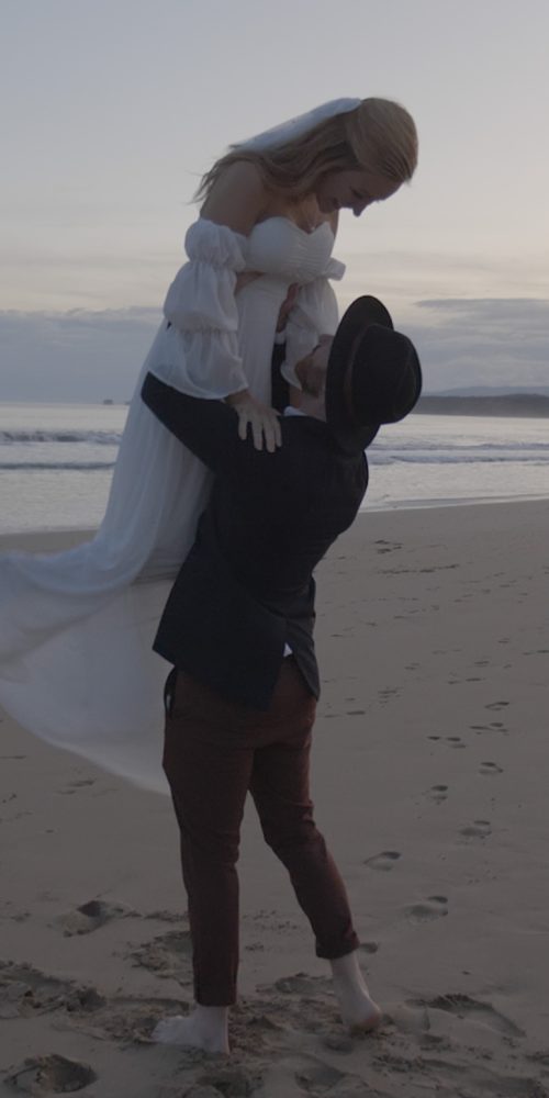 a groom lifts his bride into the air on their wedding day